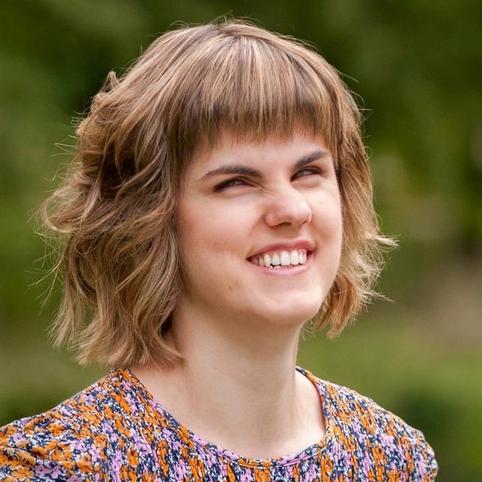 Rachel Starrit, a young woman with fair skin tone and shoulder-length blond hair wearing a floral top and smiling.