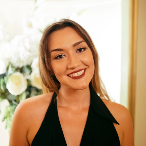 Ruth Potts, a young woman with light skin tone and shoulder-length blonde hair wearing a black dress.